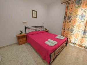 ein Schlafzimmer mit einem roten Bett mit zwei Handtüchern darauf in der Unterkunft Elena Pool in Agios Georgios