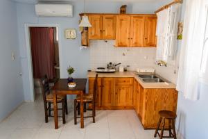 a kitchen with wooden cabinets and a table and a sink at Theodora in Panormos