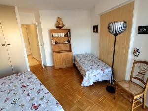 a bedroom with two beds and a chair and a book shelf at Le Masters in Mandelieu-la-Napoule +5 photos