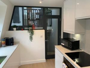 a kitchen with white cabinets and a black door at One Bedroom Apartment London in London
