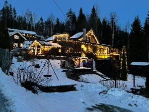 a house covered in christmas lights in the snow at Stabbur Steinbekken Roost, Rustic Forest Stay, Shared Toilet, No Shower in Eidsvoll