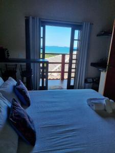 a bedroom with a bed with a view of the ocean at Burung Flats Itamambuca - Hospedagem com vista para o mar in Ubatuba