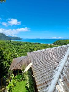 een dak van een huis met de oceaan op de achtergrond bij Burung Flats Itamambuca - Hospedagem com vista para o mar in Ubatuba