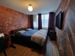 1 dormitorio con 1 cama y pared con un mural de árboles en 500-Mb Hi-Tech Silent Work-Home en Ámsterdam