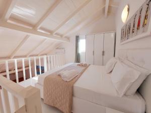a white bedroom with a bed and a staircase at Branco Sea Holiday Apartments in Santa Maria
