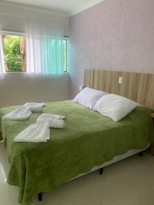 a bedroom with a green bed with pillows and a window at Casa em Riviera de São Lourenço in Bertioga