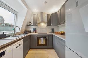 a kitchen with gray cabinets and a sink and a window at Chelsea Superior Apartment - 10 Minutes from Stadium in London