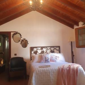 a bedroom with a white bed and a chair at La Gallania de Papá Pepe in Santa Lucía