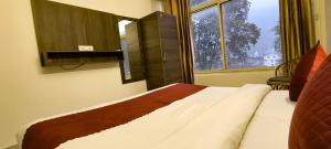 Bett in einem Zimmer mit einem großen Fenster in der Unterkunft Hotel Grace Ganga in Rishikesh