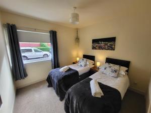 sypialnia z 2 łóżkami i oknem z samochodem na zewnątrz w obiekcie Large 3 bed, great for contractors, with private parking w mieście Provanmill