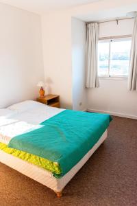 ein Schlafzimmer mit einem Bett mit einer grünen Decke darauf in der Unterkunft PH Patagonia Barrancas al Mar 2 in Puerto Madryn + 10 Fotos