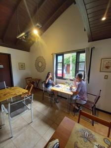 two people sitting at a table in a restaurant at Pousada Lagoa do Rosa in Praia do Rosa