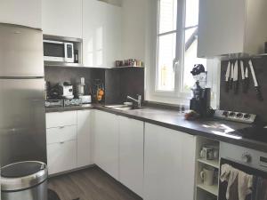 uma cozinha com armários brancos e um frigorífico de aço inoxidável em JO 2024/ 10min Stade de France em Enghien-les-Bains