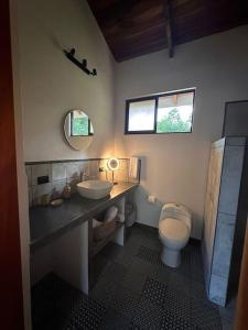 een badkamer met een wastafel, een toilet en een spiegel bij Cabañas Areno Lodge in Bijagua