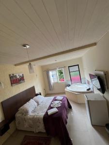 a bedroom with a bed and a bath tub at Pousada La Sierra in Campos do Jordão