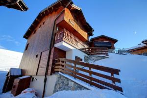 un edificio de madera con escaleras en la nieve en Chalet Topaz - 18 Couchages Sur les Pistes avec Services, en Plagne Villages