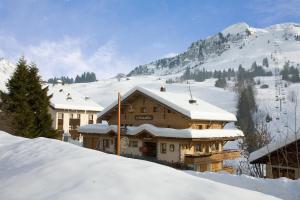 a building in the snow with mountains in the background at Hotel La Crémaillère in Le Grand-Bornand