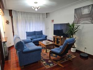 Sala de estar con 2 sillas azules y TV en APARTAMENTO VALDEARENAS, en Renedo de Piélagos