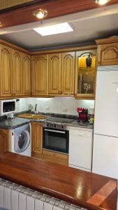 cocina con armarios de madera y nevera blanca en APARTAMENTO VALDEARENAS, en Renedo de Piélagos