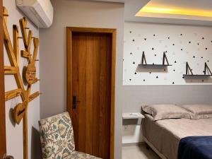 ein Schlafzimmer mit einem Bett und einem Stuhl neben einer Tür in der Unterkunft Triplex independente in Cabo Frio