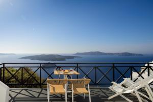 a table and chairs on a balcony overlooking the water at Kamares Apartments in Fira
