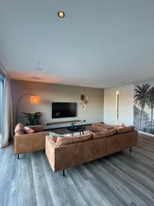 uma sala de estar com 2 sofás e uma televisão de ecrã plano em Waterside Voorthuizen em Voorthuizen
