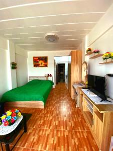芭達雅中心的住宿－Nirun Grand Ville C4，一间卧室配有绿色的床和电视