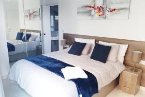 1 dormitorio con 1 cama grande con almohadas azules y blancas en New Seafront apartment – Spectacular views en St. Paul's Bay