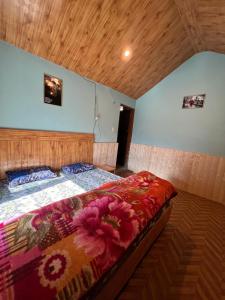 a bedroom with a bed with a colorful comforter at Lee Garden Himalayan Wooden Cottages in Kasol