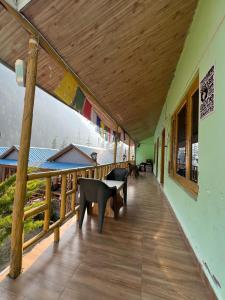 un balcón con mesas y bancos en un edificio en Lee Garden Himalayan Wooden Cottages, en Kasol