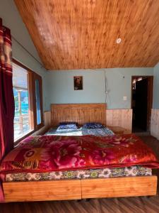 a bedroom with a large bed with a wooden ceiling at Lee Garden Himalayan Wooden Cottages in Kasol