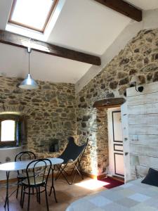 um quarto com uma parede de pedra com uma mesa e cadeiras em Mas la Tabatière em Chamborigaud