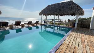 a swimming pool with chairs and a straw umbrella at AZVLIK in Rivas