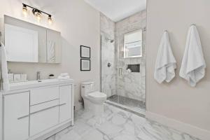 a white bathroom with a toilet and a shower at Luxury 1 Bedroom Condo In The Heart Of Cable Beach! in Nassau