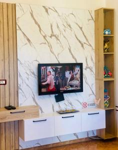 a tv on a wall with a marble wall at Baka Guest House in Durrës