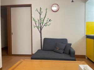 a blue couch in a room with a tree on the wall at Happy House- TAKAMATSU in Takamatsu