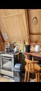 a kitchen with a stove and a table and a chair at Refugio de bosque altos de ñancul in Panguipulli