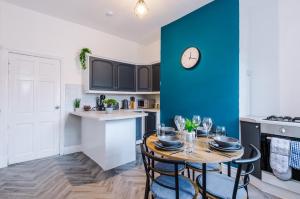 a kitchen with a table and a blue wall at Entire house in Dukinfield in Dukinfield