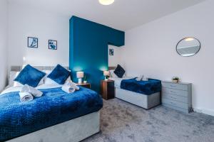 a bedroom with two beds and a blue wall at Entire house in Dukinfield in Dukinfield