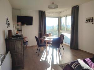 un soggiorno con tavolo, sedie e una finestra di Casa Del Cargol terrasse plein sud avec vue et garage a Font-Romeu-Odeillo-Via