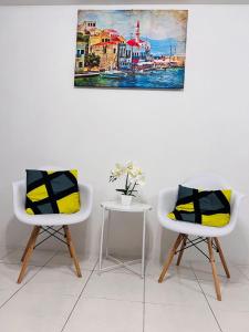 2 Stühle und ein Tisch mit einem Gemälde an der Wand in der Unterkunft Hafizah Homestay Bangi-Kajang in Kajang