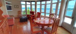 a dining room with a table and chairs and windows at Apartamento turístico en Porto do Son in Porto do Son