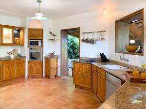 a large kitchen with wooden cabinets and a tile floor at Villa Palm Bay Stunning View 5 min to beach 3 min to downtown King size bed in Deshaies