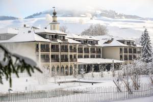 a large building covered in snow with a roof at Resort Hof Weissbad in Weissbad