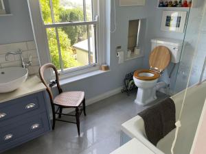 baño con lavabo y aseo y ventana en Lovely Charmouth cottage with log fire & garden close to beach, en Charmouth