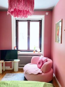 a pink room with a pink chair and a window at Värikäs koti lähellä keskustaa in Helsinki