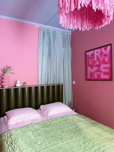 a bedroom with a green bed and pink walls at Värikäs koti lähellä keskustaa in Helsinki