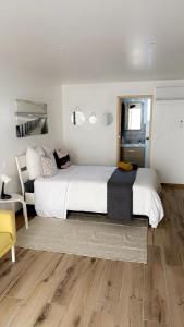 a bedroom with a large white bed and a yellow chair at Chambre le Petit Olivier in Arles