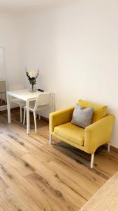 uma sala de estar com um sofá amarelo e uma mesa em Chambre le Petit Olivier em Arles