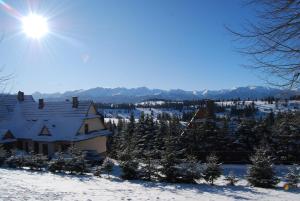 a house in the snow with the sun behind it at Willa Cisyna in Gliczarów